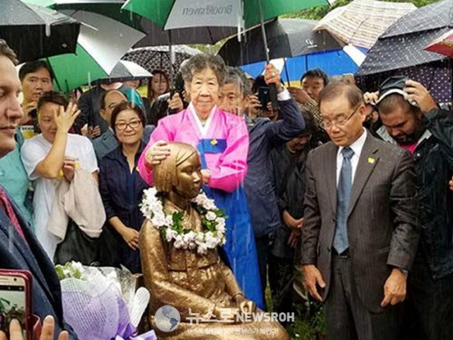 President of the Task Force Baik Kyu Kim looks at the Statue as Grandma Kang strokes the Statue.jpg